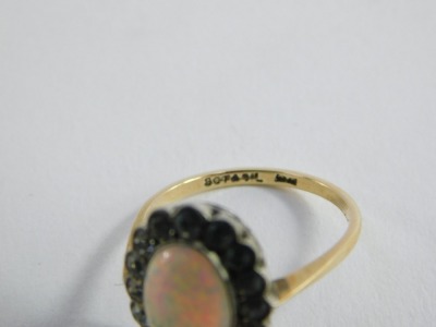 A 9ct gold opal dress ring, the central oval opal in platinum rub over setting, surrounded by tiny white stones, on a raised basket setting, on yellow gold band marked 9ct and sil,  size M, 2.5g all in, boxed.  - 6