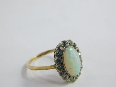 A 9ct gold opal dress ring, the central oval opal in platinum rub over setting, surrounded by tiny white stones, on a raised basket setting, on yellow gold band marked 9ct and sil,  size M, 2.5g all in, boxed.  - 7