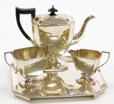 A George V silver three piece tea service, comprising teapot, two handled sugar bowl and milk jug, each with a shaped body and angular handles on a shaped pedestal base, the teapot with an ebonised knop and handle, makers marks for Stevenson and Law, Shef