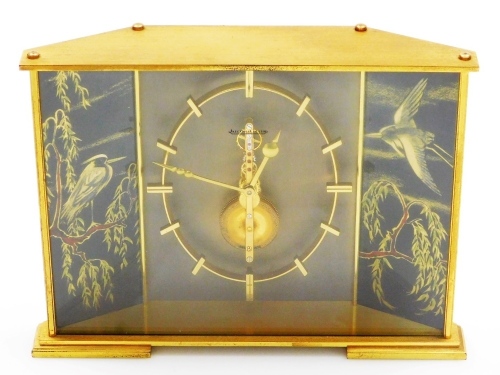 A Jaeger LeCoultre brass mantel clock in the Japanese style, the brass skeleton eight day movement inset with red/pink coloured stones, the dial flanked by two panels depicting birds, branches, leaves, etc., 15cm high, 20cm wide, 5cm deep.