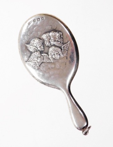 A George V silver hand mirror pendant, decorated with five embossed cherubs, with an oval mirror plate with pendant loop, Birmingham 1914, 6.5cm high.