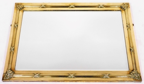 An early 20thC brass framed wall mirror, cast with scrolls, leaves, with a raised border, etc., 59cm x 84cm.