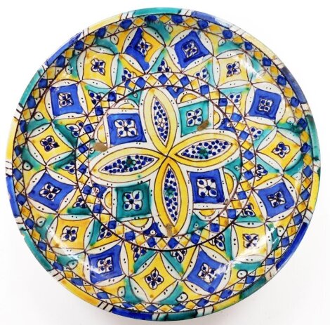 An Iznik faience pottery charger, of circular form, profusely decorated with flowers and geometric diamonds, predominantly in yellow, green and blue, 32cm diameter.