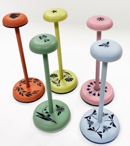 Five hand painted hat stands, with compressed mushroom tops, plain cylindrical stems, and circular bases, each stencilled and hand painted in Farrow and Ball paint, to include star, horse head, bee, etc., in varying colours, 28cm high. (5)