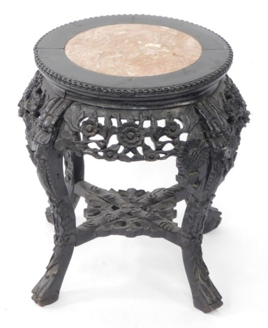 A Chinese 19thC hardwood and marble urn stand, the circular top raised on four dragon carved cabriole legs with floral frieze carving, united by a carved under tier, 50cm high, 50cm diameter.