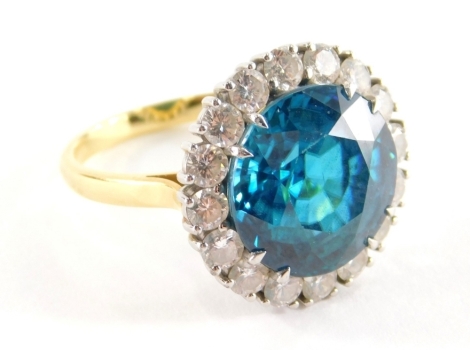 A blue zircon and diamond cluster ring, with central blue zircon totalling 13.1cts, within a border of sixteen round brilliant cut diamonds, in white gold setting totalling approx 1.6cts, on a yellow gold shank, 18ct gold, London 2006, with C Limited spon