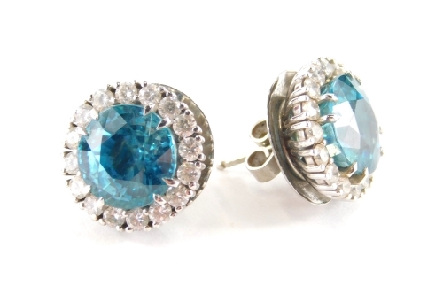 A pair of blue zircon and diamond cluster earrings, each centred by a round cut zircon totalling approx 10.5cts, within a border of sixteen round brilliant cut diamonds totalling approx 1ct overall, claw set to platinum mount with peg and butterfly fittin