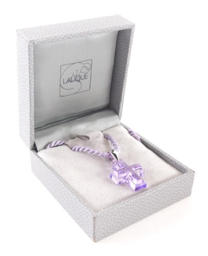 A lilac Lalique crucifix pendant, on a purple rope twist string, the pendant 2.5cm high, boxed.