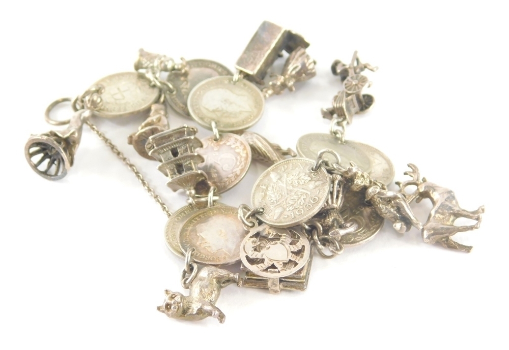 A silver coin charm bracelet, the bracelet comprising three pence pieces,  with various silver and silver