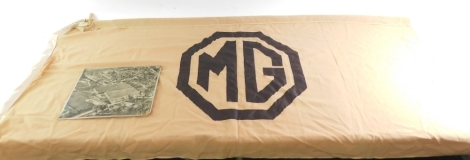 An MG flag, originally from the MG factory, and the last flag to be flown before its closure, in a brown hessian material finish with brown leather MG badge, 184cm x 90cm, together with an ariel photograph of the factory, on metal. (2)