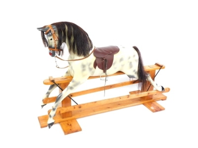 A Haddon Rockers rocking horse, the dappled horse with a maroon leather seat, on a pine base with Haddon Rockers plaque, 116cm high, 150cm wide, 62cm deep.