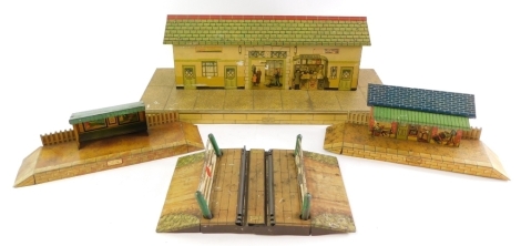 A Hornby tin plate railway station, with book stall, together with a platform waiting room, platform shelter and a level crossing. (4)