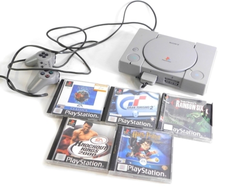 A Sony Playstation 1, with controller, and five games, Grand Tourismo II, Popelovs The Beginning, Tom Clancy's Rainbow Six, Knockout Kings 2000, Harry Potter and The Philosophers Stone, and memory card.