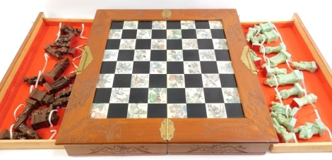 An Eastern hardwood chess set, the half fold box opening to reveal Eastern decorated white and black panels, with thirty two chess pieces, boxed.