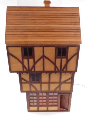 A wooden Tudor style doll's house, three storeys, with thatched roof.