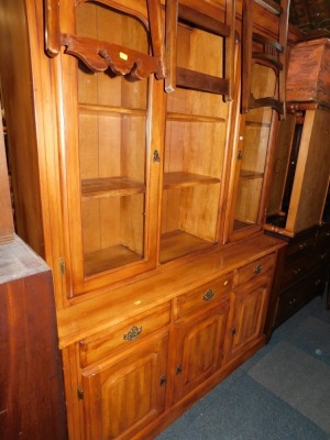 A hardwood dining room cabinet, with two shelves, flanked by glazed cabinets, raised above three drawers and three cupboards.