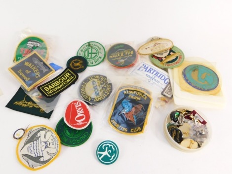 A collection of fishing badges, to include enamelled and pewter pin badges, and sew on patches for various manufacturers and fisheries. (1 tray)