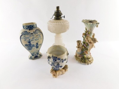 A Victorian milk glass oil lamp base, a Delft vase, continental late 19thC porcelain candelabrum base decorated with cherubs and encrusted with flowers, and a continental porcelain vase. (4)