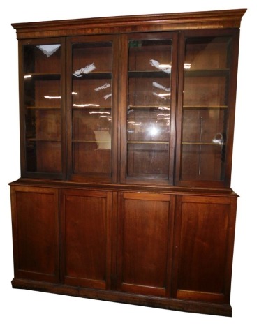 A Victorian mahogany library bookcase, the out swept pediment over two pairs of glazed doors, each opening to reveal three shelves, above four cupboard doors, raised on a plinth base, 244cm high, 196cm wide, 45.5cm deep.