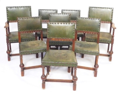 A set of eight Carolean revival oak dining chairs, with studded green leather backs and overstuffed seats, raised on turned legs, united by an H frame stretcher, comprising a pair of carvers and six single chairs.