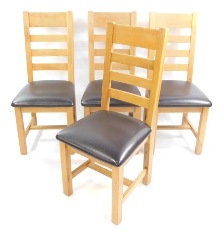 A set of four light oak ladder back single dining chairs, with over stuffed leather seats.