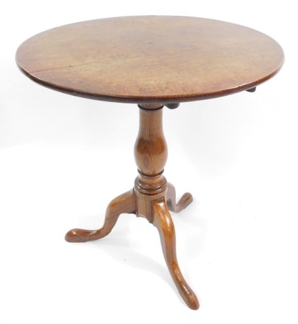 A Georgian early 19thC oak occasional table, with circular top, raised on a baluster turned column, above three cabriole legs, 69cm high, 60cm diameter.