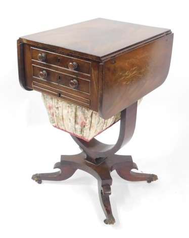 A Victorian flame mahogany drum sewing table, the drop leaf top above two frieze drawers, and a linen bound drum, raised on a U shaped support, above a quatrefoil base, over out swept legs, brass paw capped on castors, 67.5cm high, 36cm wide, 74cm extende