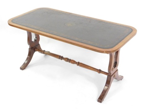 A Georgian style mahogany coffee table, the oblong top inset with gilt tooled green leather, raised on lyre shaped end supports, united by a turned stretcher, 42cm high, 90cm wide, 45cm deep.