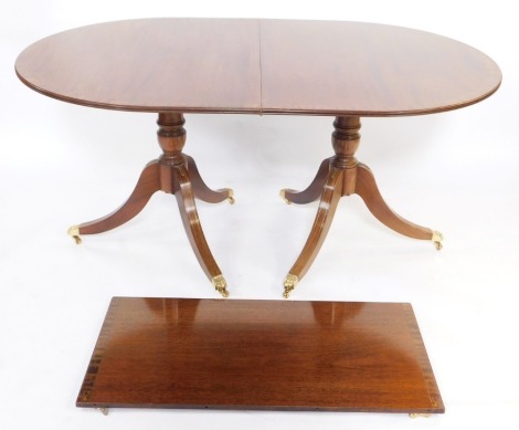 A Georgian style mahogany and brass inlaid twin pedestal dining table, with baluster turned columns, over three sabre legs, brass paw capped, 75cm high, 210cm wide, 101cm deep.