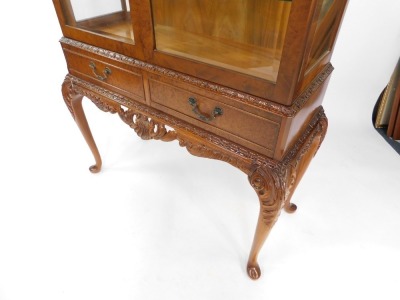 A Chechik Limited mid century burr walnut display cabinet, the foliate carved top above a pair of doors, enclosing two glass shelves, above a pair of frieze drawers, over leaf carved cabriole legs, 158cm high, 90cm wide, 37.5cm deep, - 3