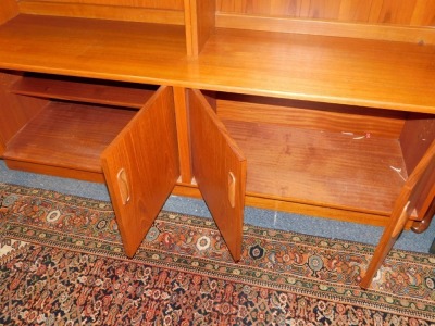 A G-Plan 1960's teak lounge unit, the two section top with an arrangement of five shelves and a drop down drinks cabinet, above a sideboard base with four doors, raised on a plinth base, 198cm high, 162.5cm wide, 46cm deep. - 2