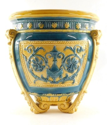 A Wedgwood late 19thC blue and yellow pottery jardiniere, moulded with panels of classical vases, flowers and foliate scrolls, raised on three leaf moulded scroll feet, impressed and painted marks, 34cm high, 32cm wide. (AF) - 3