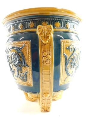 A Wedgwood late 19thC blue and yellow pottery jardiniere, moulded with panels of classical vases, flowers and foliate scrolls, raised on three leaf moulded scroll feet, impressed and painted marks, 34cm high, 32cm wide. (AF) - 6