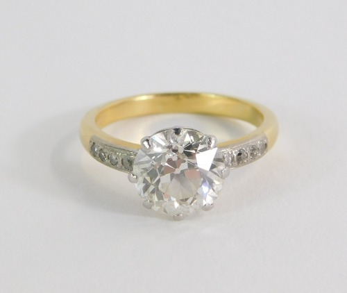 A diamond solitaire ring, with round brilliant cut diamond, measuring 8.4mm x 5.8mm, approx 2.5 carats overall, in a eight claw raised basket, platinum setting, with four tiny diamonds set shoulders, on yellow gold band, marked 18ct, size P, 5g all in.