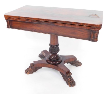 A Regency mahogany fold over card table, with canted corners, opening to reveal a red lined table interior, on a lappet carved column and quatrefoil base, on lion's paw feet, 71.5cm high, 91cm wide, 44cm deep. (AF)