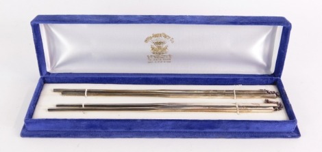 Two pairs of silver chop sticks, each pair with engraved decoration, and chain linked, stamped 925 and sterling, 22cm long, 4¼oz gross, in an Ellis Jewellery Hong Kong fitted box.