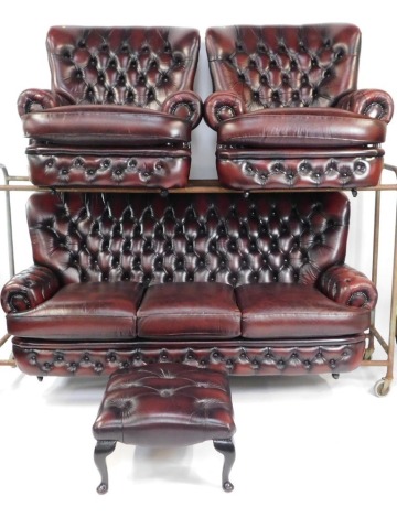 A maroon leather button back Chesterfield sofa suite, comprising three seater sofa, two matching armchairs and a footstool, each with button back detailing, the sofa 106cm high, 200cm wide, 73cm deep, armchairs both 106cm high, 91cm wide, 81cm deep. (4)