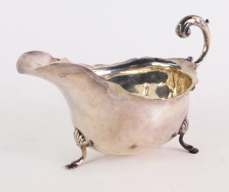 A George V silver sauce boat, with an s scroll handle, raised on three hoof feet, Chester 1926, 3oz. (AF)