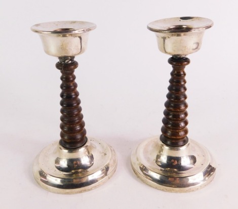 A pair of George V loaded silver candlesticks, each with a turned graduated wooden stem, with silver top and circular base, Chester 1926, 15cm high.