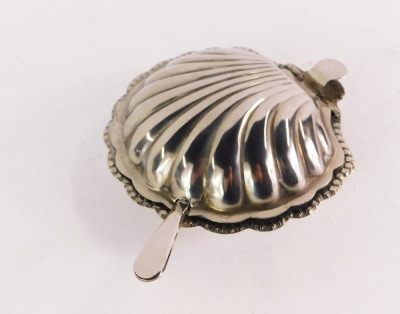 A silver plated scallop shell butter dish, with glass lined interior and butter knife.