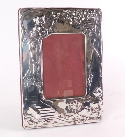 An Art Nouveau style silver photograph frame, the outer rim with embossed figures of females picking roses, maker's stamp PJP, Birmingham 1984, with a red velvet back, picture size 13cm x 8.5cm, frame size 25cm x 17.5cm.