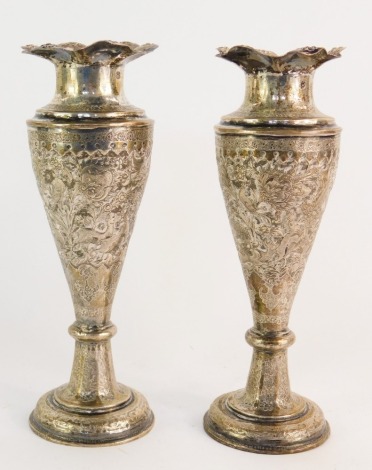 A pair of Eastern hammered vases, with a flared rim and repousse decorated with animals, birds and flowers, on a stepped base, marks to neck, white metal, 23cm high, 22½oz gross.