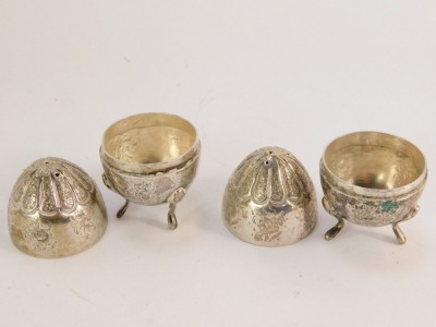 A pair of Eastern salt and pepper shakers, of ovoid form with engraved floral detailing, on three scroll feet, white metal, unmarked, 3½oz. - 2