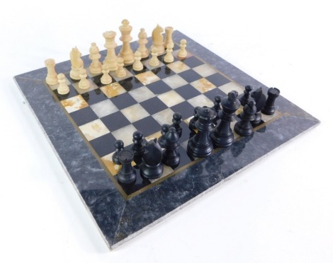 A marble and onyx set chess board, together with a French set of Staunton type wooden chess pieces, boxed, the board 25cm x 25cm, the King 5cm high.