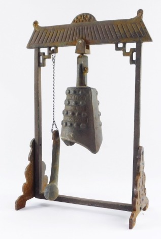 A Tibetan cast iron temple bell, on arched support, with bell and strike, 36cm high, 24cm wide, 12cm deep.