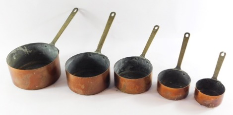 A set of five 19thC graduated copper saucepans, each with brass handles, the largest 16cm diameter, the smallest 7cm diameter.