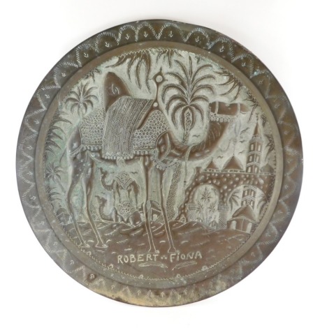A hammered copper charger, with palm tree and camel detailing, marked Robert and Fiona, 66cm diameter.