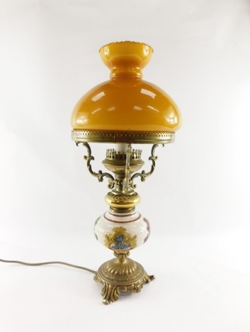 A 20thC oil lamp style electric table lamp, with orange glass shade on a brass three prong support, with glazed and floral print body on rococo foot, 52cm high. WARNING! This lot contains untested or unsafe electrical items. It is supplied for scrap or r