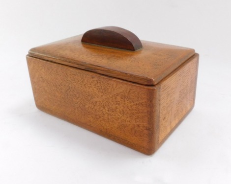 A 1930's oak cigarette box, with moulded corners, raised handle, 10cm high, 15cm wide, 9.5cm deep.