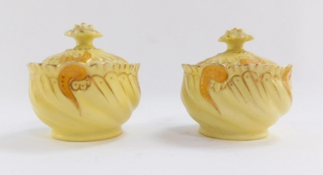 A pair of Limoges porcelain dressing table jars and covers, in yellow and orange detailing with rosette top, 7cm high.